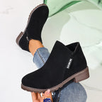 Black ankle boots held in hand, close-up