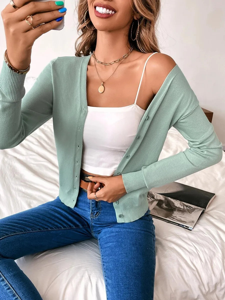 Sage green V neck cardigan worn off the shoulder over a white cami