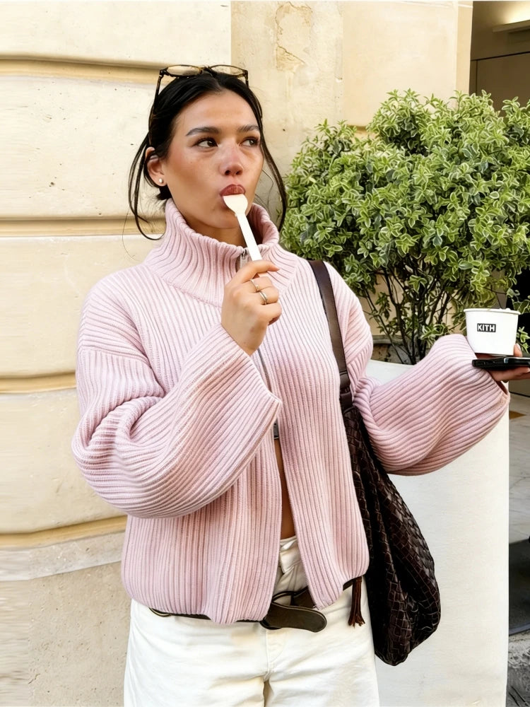 Pale pink knit zip up cardigan worn with a high neck