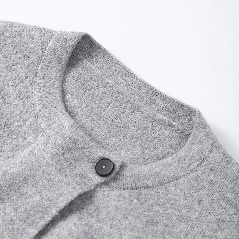 Close-up of the round neckline and single button on a grey cardigan