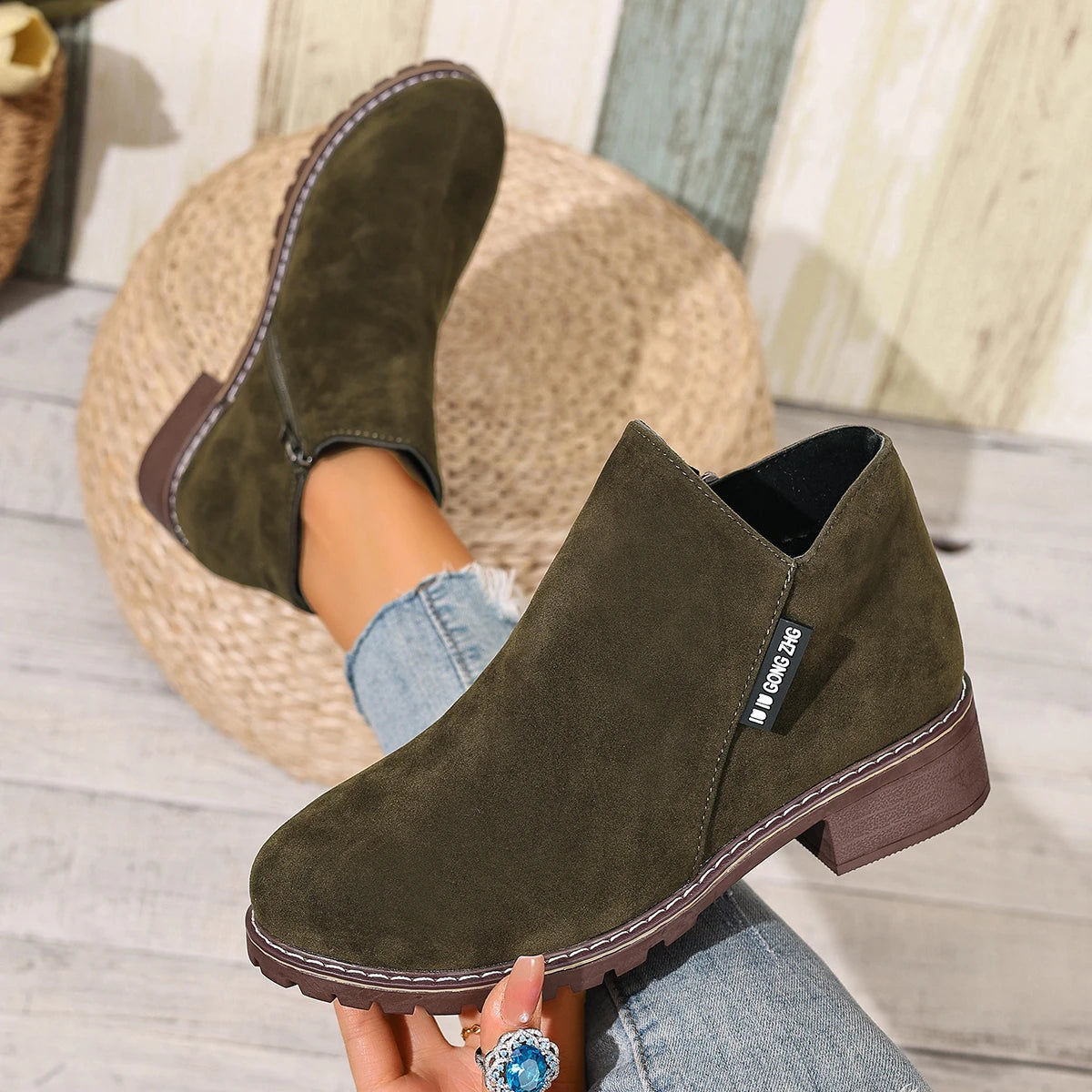 Olive green ankle boots held in hand, close-up