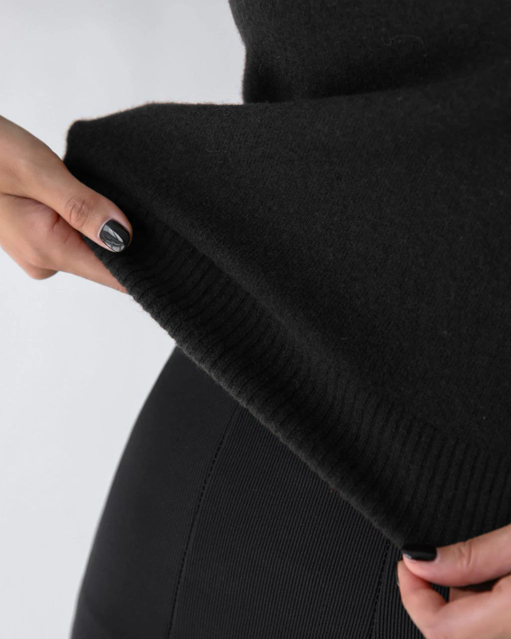 Close-up of the ribbed hem on a black knit cardigan