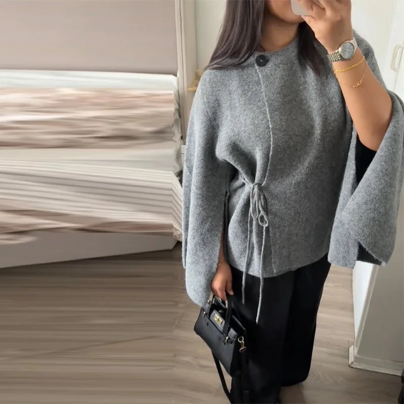 Grey tie side cardigan with flared sleeves, worn with black trousers