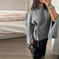 Grey tie side cardigan with flared sleeves, worn with black trousers