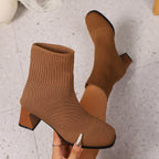 Tan brown knit sock ankle boots with block heel, held in hand, close-up