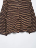 Patch pocket and hem detail on a brown and tan check knit cardigan
