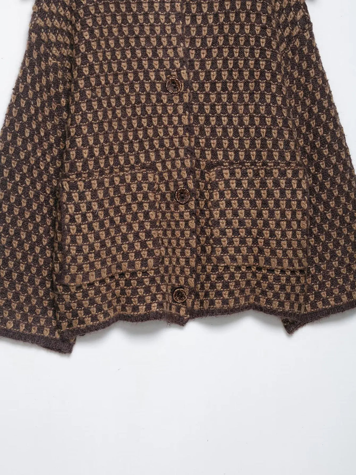 Patch pocket and hem detail on a brown and tan check knit cardigan