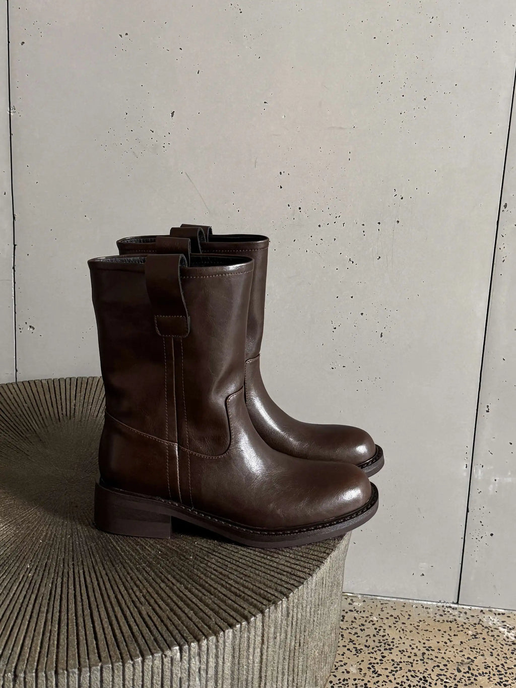 Brown leather mid calf western boots on a stone surface