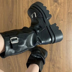 Black matte faux leather biker boot with metal buckle strap, close-up