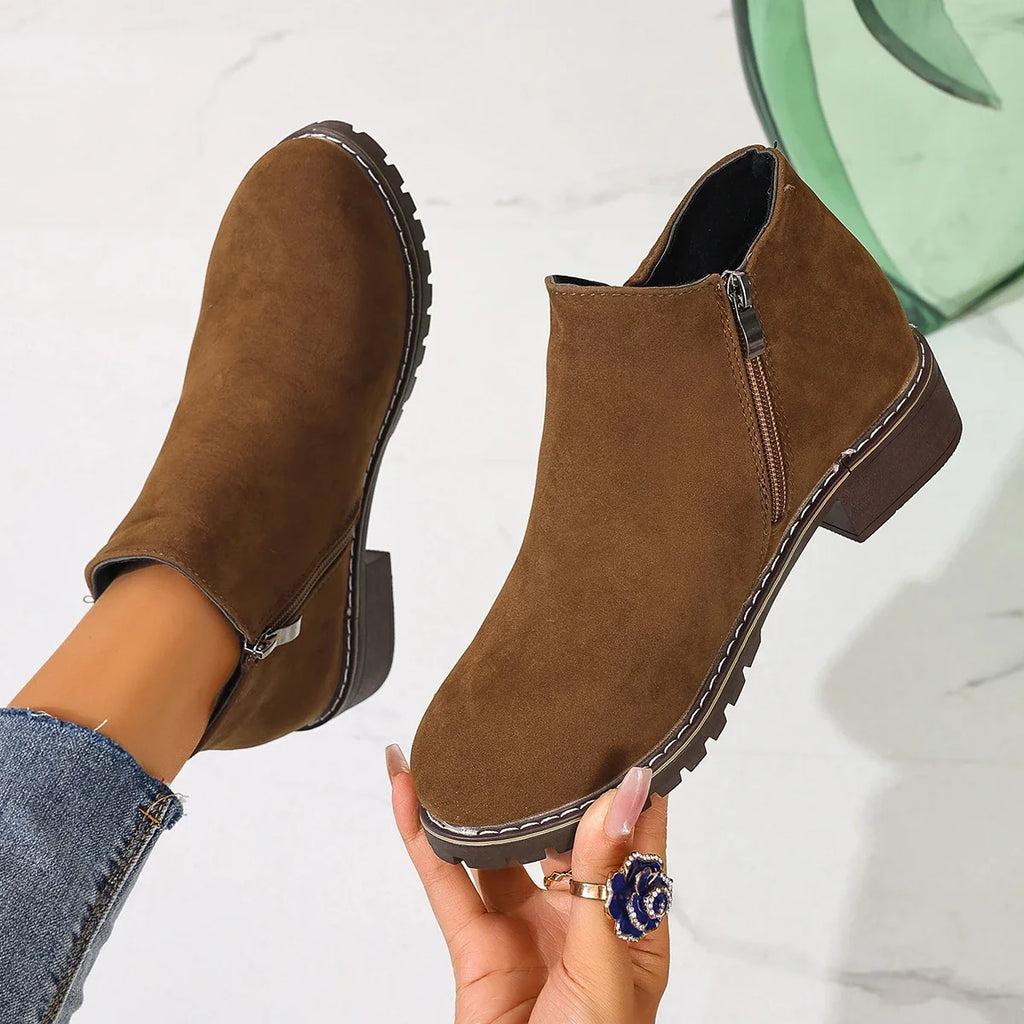 Brown ankle boots held in hand, close-up