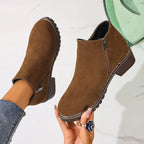Brown ankle boots held in hand, close-up