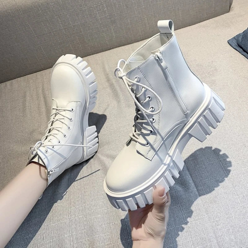 White lace-up ankle boots with chunky ridged sole and side zip, held in hand