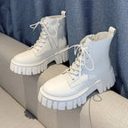 White lace-up ankle boots with chunky sole resting on a sofa