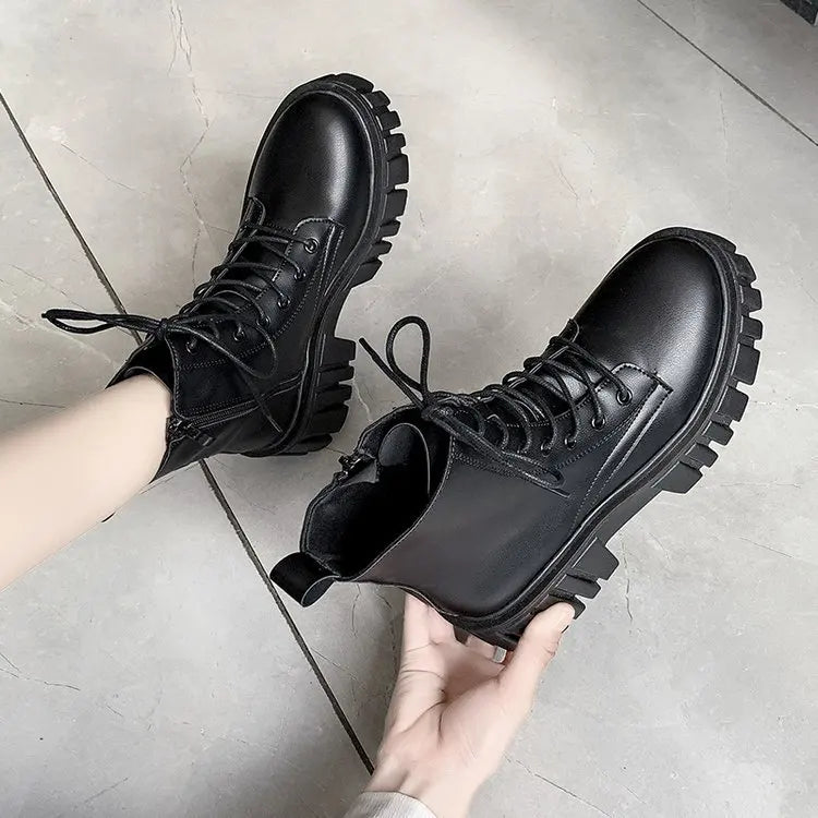 Black faux leather lace-up ankle boots with round toe, held in hand