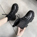 Black faux leather lace-up ankle boots with round toe, held in hand