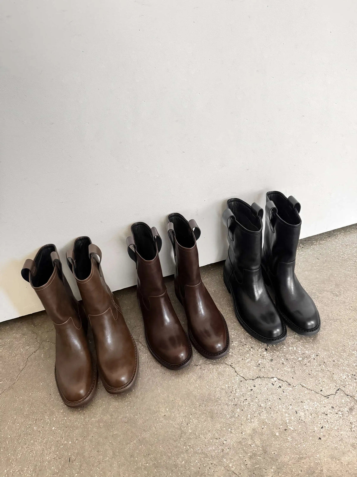 Black and brown leather mid calf western boots lined up side by side