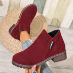 Burgundy ankle boots held in hand, close-up
