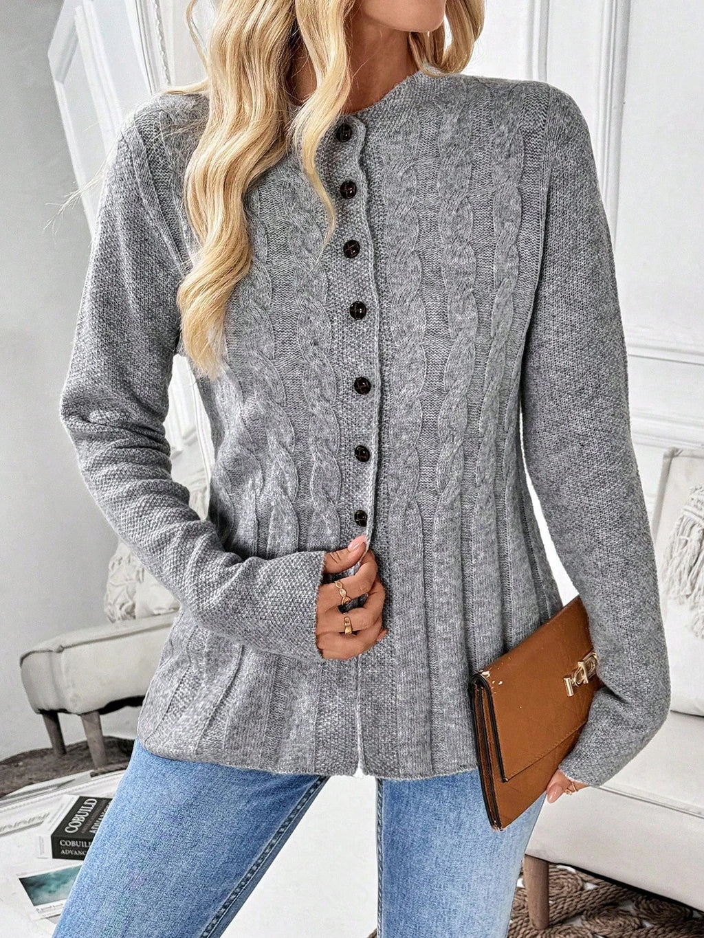 Grey cable knit cardigan with black buttons worn open at the hem